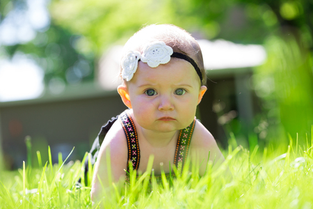 Baby girl at roughly 6 months old outdoors in a natural setting with available light for a lifestyle portrait.の写真素材