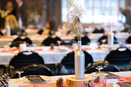 Decorations for an indoor wedding reception in the winter include painted bottles with white...
