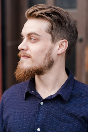 Hipster posing outdoors for the camera with a fashion forward style and a modern man appearance.