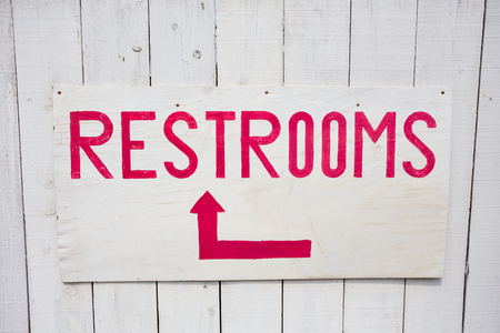 Restrooms sign in red and white mounted on a building in Oahu Hawaii.の写真素材