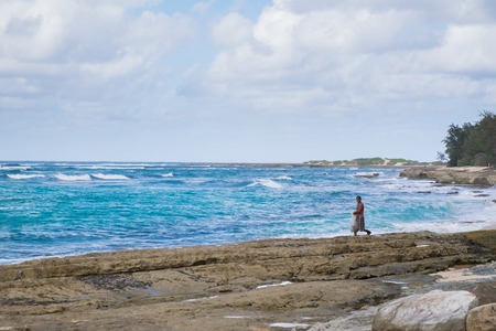 TURTLE BAY, OAHU, HAWAII - FEBRUARY 21, 2017: Net fisherman walks across rocks in heavy surf at the beach near Turtle Bay Resort on the North Shore of Oahu Hawaii.のeditorial素材