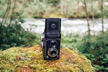 BELKNAP, OR - APRIL 24, 2015: Yashica A TLR medium format camera propped outdoors on a mossy rock with the McKenzie River of Oregon in the background.のeditorial素材