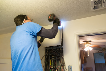 SPRINGFIELD, OR - DECEMBER 23, 2016: Electrician using a mutli-tool to open up the top of an electrical panel during a service change as part of a major house renovation.のeditorial素材