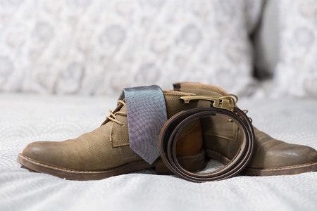 Groom wedding clothing shows a sense of vintage style with simple fashion from handmade leather items including a belt, shoes, and a nice grey tie.の写真素材