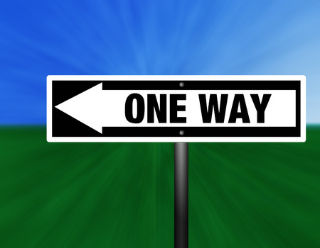 A black and white one way street sign against a sky and grass background.の写真素材