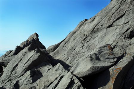 This is a picture of a big rock in a sunny day with a blue sky.の写真素材