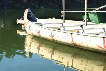 It is a indian canoe floating over a river on a sunny day.