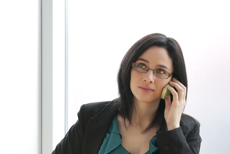 This is a businesswoman holding a green cell phone seriously.の写真素材