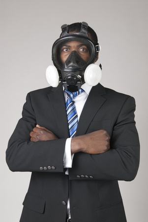 This is a black businessman waring a gas mask isolated over a gray background.の写真素材