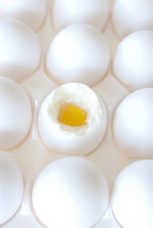 This is a bunch of white eggs in a white crete and one is open and half cooked.の写真素材