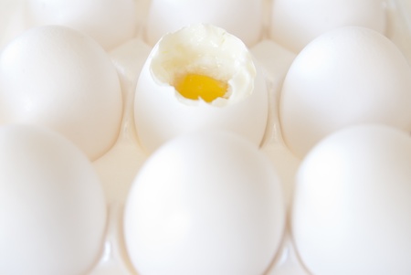 This is a bunch of white eggs in a white crete and one is open and half cooked.