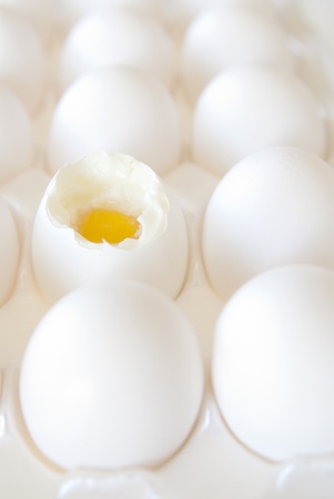 This is a bunch of white eggs in a white crete and one is open and half cooked.の写真素材
