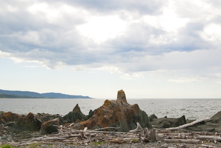 This is a bunch of big rocks close to the sea over a blue cloudy sky.の写真素材