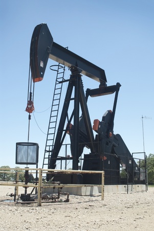 This is a pump jack in a middle of a field pumping the oil out of the ground.の写真素材