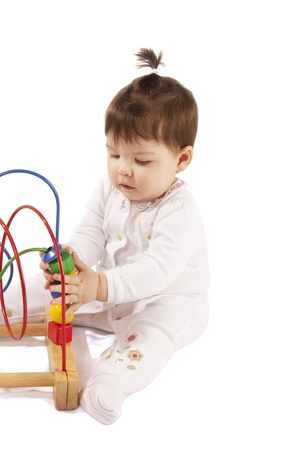 This is a little baby girl playing with a colorful toy isolated over a white background.の写真素材