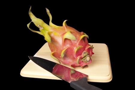 This is a dragon fruit over a cutting board on a black background.の写真素材