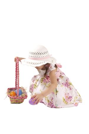 This is a little girl looking for eggs at Easter with a white dress and isolated on a white background.の写真素材