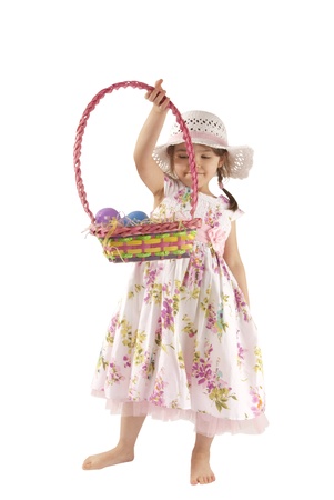 This is a little girl looking for eggs at Easter with a white dress and isolated on a white background.の写真素材