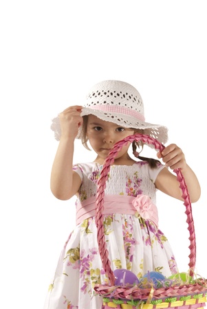This is a little girl looking for eggs at Easter with a white dress and isolated on a white background.の写真素材