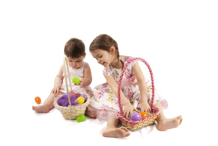 This is two little girls looking for eggs at Easter with a white dress and isolated on a white background.の写真素材
