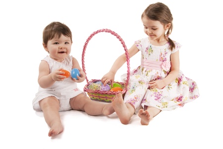 This is two little girl with a dress playing with eggs for Easter isolated on a white background.の写真素材
