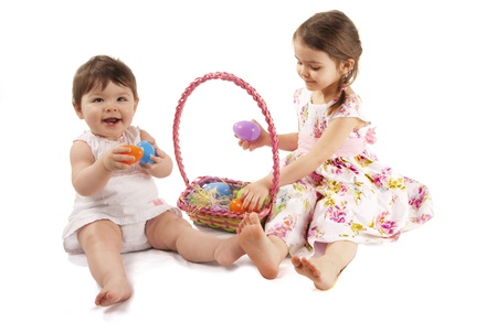 This is two little girl with a dress playing with eggs for Easter isolated on a white background.の写真素材