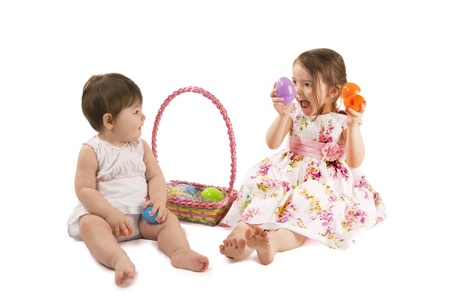 This is two little girl with a dress playing with eggs for Easter isolated on a white background.の写真素材