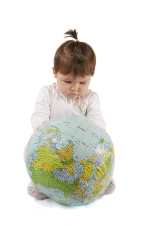 Little baby girl playing with an inflatable globe isolated over a white background の写真素材