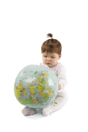Little baby girl playing with an inflatable globe isolated over a white background の写真素材
