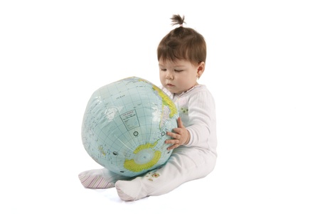Little baby girl playing with an inflatable globe isolated over a white background の写真素材