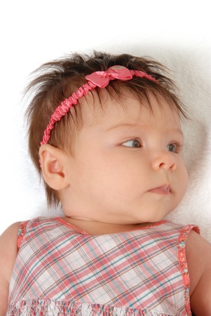 A close-up of a baby girl laying down on a white background.の写真素材