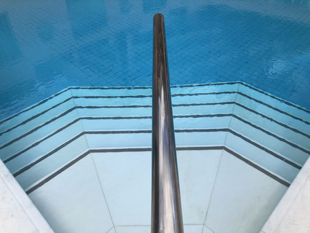 Tiled steps in to a swimming pool with a stainless steel handrailの写真素材