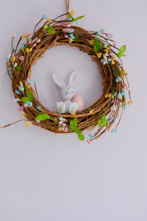 Easter bunny in a wreath hanging on a wall, isolated with copy space