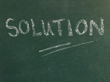 The word Solution written in white chalk on a chalk board, with copy spaceの写真素材