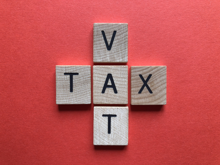 VAT (acronym for Value Added Tax) and Tax in 3d wooden alphabet letters on a bright red backgroundの写真素材