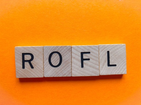 Internet slang, Acronym ROFL (Rolling on floor laughing) in wooden letters on a bright orange background with copy spaceの写真素材