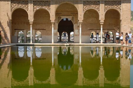 Reflections in pond water and visitors at the open portico of Torre de las Damas, Tower of The Ladies, Partal, The Alhambra, Granada, Andalusia, Spainのeditorial素材