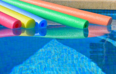 pool noodles floating in a swimming pool. Summer vibes, bright and colourful, keeping cool