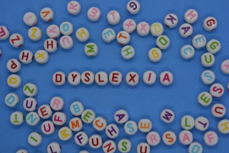 Dyslexia, spelt out in red letters, surrounded by a sea of random letters, on a blue background. ...