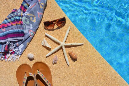 Summer holiday flat lay. Sandals, starfish, seashells, sunglasses and a beach wrap, all on the side...