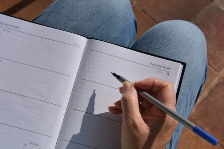 Woman writing in diary, pen in hand
