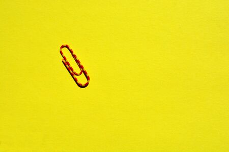 One red and yellow plastic coated  paper clip isolated on yellow background with copy spaceの写真素材