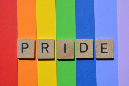 Pride, word in 3d wooden alphabet letters isolated on rainbow striped coloured backgroundの写真素材