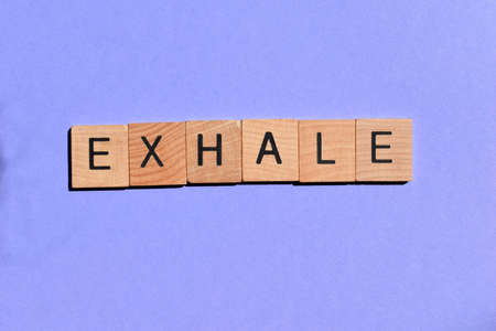 Exhale, single word in wooden alphabet letters isolated on purple background