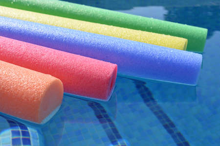 Pool noodles floating in a swimming pool. Summer vibes, bright and colourful, keeping cool
