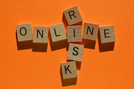 Online, Risk, words in wooden alphabet letters in crossword form isolated on orange background