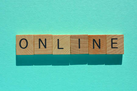 Online, word in wooden alphabet letters isolated on turquoise backgroundの写真素材