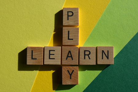 Play, Learn, words in wooden alphabet letters in crossword form isolated on green and yellow backgroundの写真素材