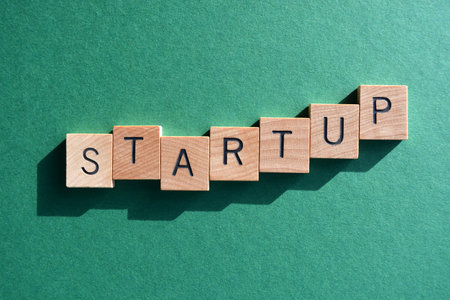 Startup, word in wooden alphabet letters isolated on green background