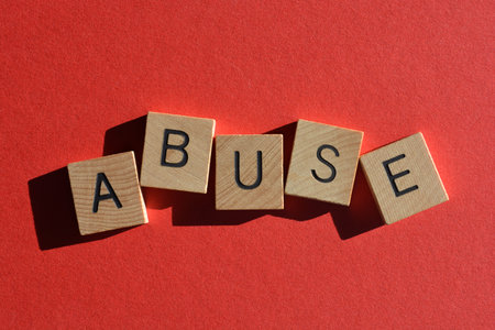 Abuse, word in wooden alphabet letters isolated on red backgroundの写真素材